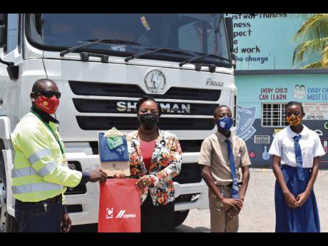Fleet driver at Caribbean Cement Company Limited Curtis Guthrie (left) makes a presentation to the principal of Watsonton Primary School, Marchelle Williams-Hinds,, during a recent visit to the institution to promote road safety among members of the studen