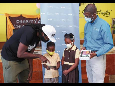 Papa Michigan (left) points out some of the features of the Samsung tablet to Kishaun Larmond and Lashronaye Hanchard, while Courtney Bell, community programmes coordinator at the FLOW Foundation, looks on.