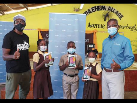 Papa Michigan (left) and Courtney Bell, community programmes coordinator at the FLOW Foundation, pause for a quick photo with students (from second left) Otania Williams, Wyenn Honeyghan and Lashronaye Hanchard.