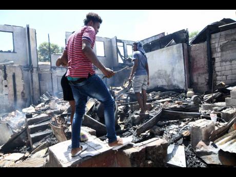 Residents forage for possessions among charred rubble after gunmen torched houses at homes along Beeston Street, central Kingston, leaving more than 30 people homeless on Tuesday.