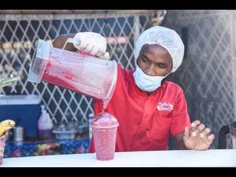 Owner of Central Smoothies, Lenard Christie, pours a freshly made Ali Berry crush, made with pineapple, blueberry and strawberry. 
