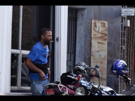A motorcyclist smokes a cigarette in the Cross Roads business district on Wednesday. Carreras Managing Director Raoul Glynn said that a sales ban and unreasonable regulation would severely affect thousands of retailers in the sector.