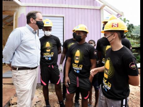 Francois Chalifour (left), director of marketing and development, Wisynco, chats with some members of the Phoenix Football Academy who volunteered to help in the constructing of a house in James Mountain, Sligoville. The house-building initiative is a part