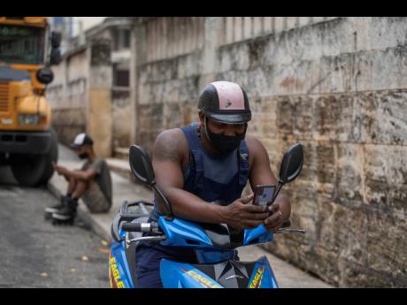 Persons using a pre-paid public wifi connection on their cell phones next to a park that’s popular for connectivity, which costs money, in Havana, Cuba, on July 14, 2021. The government responded to Sunday’s anti-government protests by shutting down in