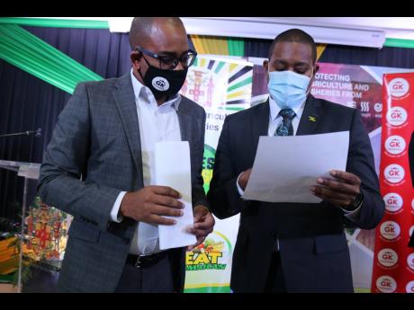 Minister of Agriculture and Fisheries Floyd Green (right) peruses an application form with Jordon Tait, assistant general manager of GK Insurance, at the launch of GK Weather Protect, a crop insurance policy developed specifically for farmers and fishers. 