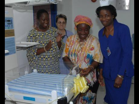 Novlin Leslie Little (left), deputy chief executive officer of the Victoria Jubilee Hospital, applauds as Rita Marley cuts the ribbon on a baby warmer that was donated to the hospital by Unlimited Resources Giving Enlightening (URGE) of the Marley Foundati