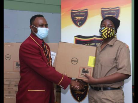 Jahlani Ustanny (right), a grade nine student of Cornwall College receives one of 115 Dell laptop computers from Dr Richard Meggo, president of the Cornwall College Alumni Association’s Montego Bay chapter, during a ceremony to hand over the devices to t