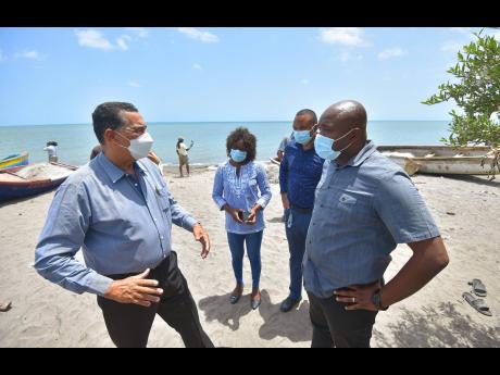 Minister of State in the Ministry of Local Government and Rural Development, Homer Davis (left), in conversation with Member of Parliament for South West Clarendon, Lothan Cousins (right), while touring a section of the community of Banks in the parish on 