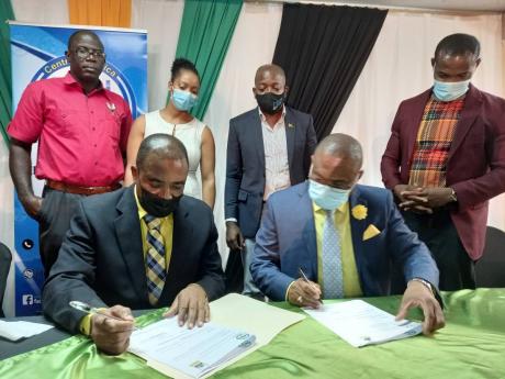 Chief Executive Officer of the Rural Agricultural Development Authority (RADA) Peter Thompson (seated, left)signs the contract for youth entrepreneurship training programme with Managing Director, Central Jamaica Social Development Initiative (CJSDI), Dami