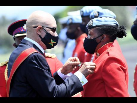 Governor General Sir Patrick Allen pins a medal on a solider yesterday during a ceremony to mark Armed Forces Day 2021 at the Jamaica Defence Force headquarters Polo Field, Up Park Camp on yesterday.