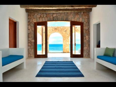 An amazingly simple interior, leads outdoors through archways to a swimming pool, above the sea.