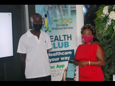 Dr Sherridene Lee (right), managing director of i-doc Concierge Wellness Services, presents a i-doc health club membership card to taxi driver Kenric Spence, who suffers from hypertension, during the launch at the Icon Mall in Fairview, Montego Bay, last T