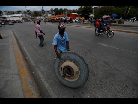 A worker rolls a tyre across the street in Port-au-Prince, Haiti, Monday, July 12, 2021.