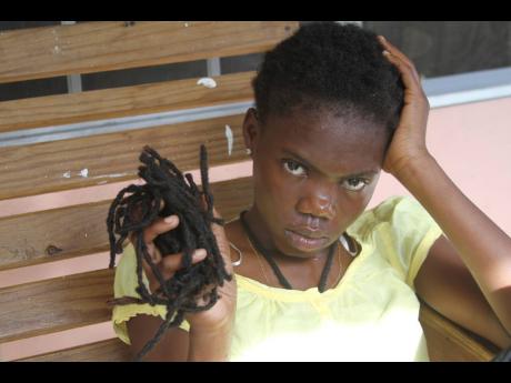Nzinga King, 19, with a handful of her dreadlocks she saved after she was allegedly trimmed by a cop.