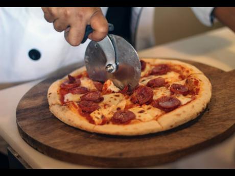 Chef Toni Yapp cuts carefully into a hot pepperoni pie.  