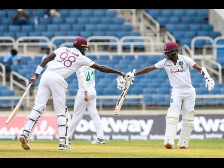 Jason Holder (left) and West Indies captain Kraigg Brathwaite touch gloves in mid-pitch during their 96-run partnership against Pakistan at Sabina Park yesterday. 