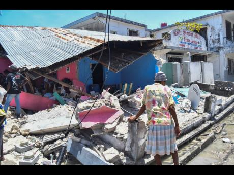 A woman stands in front of a destroyed home in the aftermath of yesterday’s earthquake in Les Cayes, Haiti