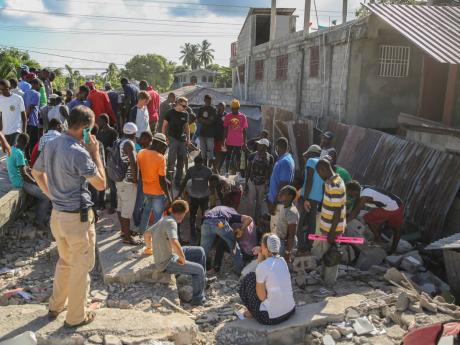 Searching for survivors in the debris of a home destroyed by the earthquake in Les Cayes, Haiti that killed over 300 people.