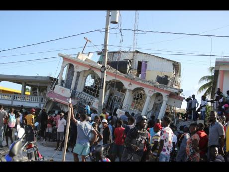 People gather outside the Petit Pas Hotel, destroyed by the earthquake in Les Cayes, Haiti