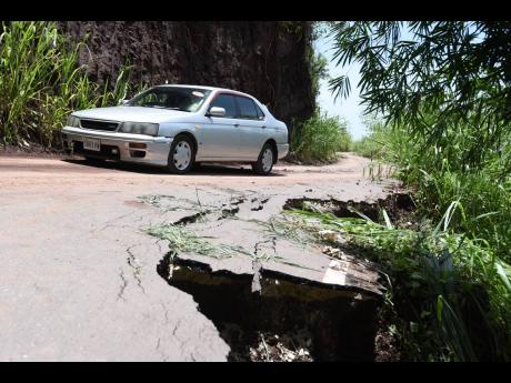 A motorist travels on Wednesday along the recently constructed Savage Pen road, sections of which have begun to collapse after torrential rain generated by Tropical Storm Grace slammed eastern parishes a day earlier. Savage Pen is the alternative route to 