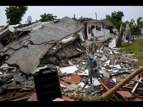 A man walks on the rubble of a collapsed hotel the morning after Tropical Storm Grace swept over Port Salut, Haiti, Tuesday, August 17, 2021, three days after a 7.2 magnitude quake. 