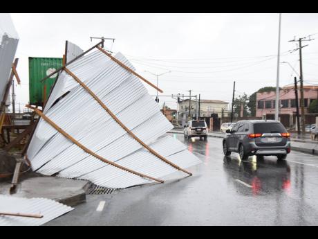 A zinc fence that was blown on to Hagley Park Road blocks one of the westbound lanes of the St Andrew corridor. Tropical Storm Grace dumped heavy rains across eastern Jamaica on Tuesday, resulting in damage to property.