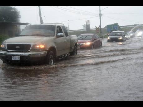 Motorists drive through floodwaters along the Old Harbour Bay main road in St Catherine during the passage of Tropical Storm Grace on Tuesday.