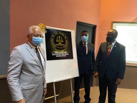 From left: Minister of Justice Delroy Chuck, Representative of Dalton Yap, pesident, Manchester Justices of the Peace Association Stanley Skeene and Custos of the Parish Garfield Green unveil the logo of the Manchester Justices of the Peace Association dui