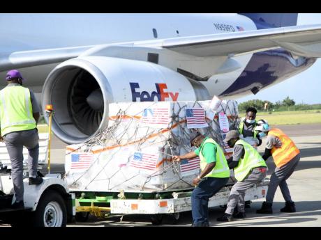 A work crew handles a shipment of 208,000 doses of the Pfizer COVID-19 vaccine, which arrived at the Norman Manley International Airport in Kingston yesterday. The vaccines were donated by the United States.