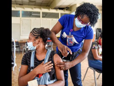 Fifteen-year-old Mya Morrison of Ascot High School winces as she braves getting the Pfizer COVID-19 vaccine from Georgia Reid, registered midwife, during the Portmore HEART Academy vaccination blitz on Saturday. 