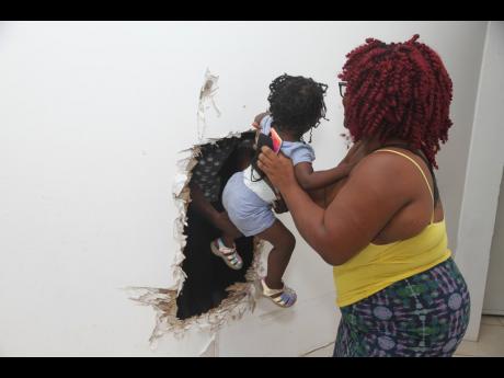 Christal Campbell shows how she passed her children through a hole in the wall to escape  floodwaters that gushed into her home during the passage of Tropical Storm Ida.