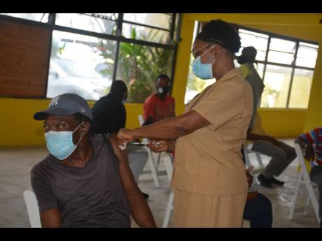 Nurse Merdella Brown-Madurie vaccinates Delroy Wisdom, AC technician at Tropical Tours, on Wednesday.