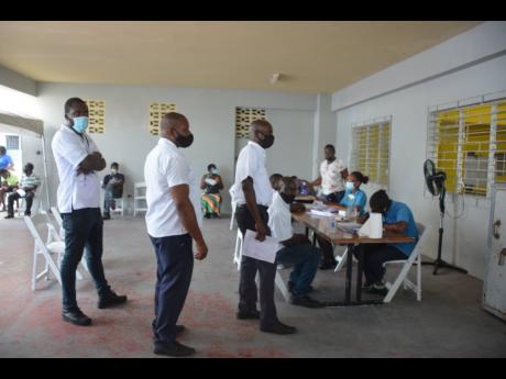 Bus drivers from Tropical Tours and Jamaica Tours wait their turn as they register for vaccinate at a blitz site on Wednesday.