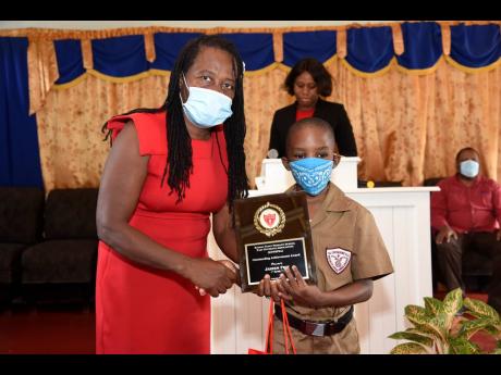 Clover Brown, a retired teacher, presents Jaheem Fray with the Outstanding Achievement Award for being one of the top-performing PEP students from Kitson Town Primary School during a luncheon at the Kitson Town Seventh-day Adventist Church on September 2.