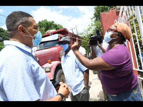 
Linette Brown (right), a resident of Grants Pen, calls on Prime Minister Andrew Holness for national prayer during his Vaccine Mobilisation and Public Education Campaign tour in North East St Andrew and Central Kingston, while Desmond McKenzie (centre), m