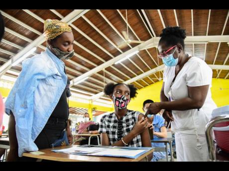Trisha Salmon (left) looks on after registered midwife Letta Coppin administered a dose of the Pfizer vaccine to her daughter, 15-year-old Aneisha Scott, at a vaccination blitz held at Merl Grove High School on Sunday.