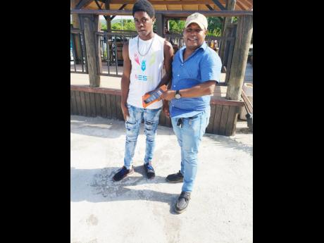 Businessman Fabian Davis (right), of Duncans Complex and Entertainment Limited, presents Nathaniel Gordon with  a tablet to help him with his online schooling.