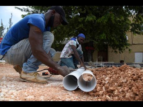 Workmen prepare to lay pipes as construction of the foundation for a field hospital continued near the Accident and Emergency Department of The University Hospital of the West Indies. The field hospital is expected to be completed by month end.