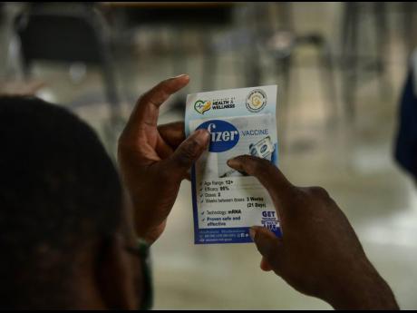 A man reads a Pfizer vaccine pamphlet issued at the vaccination blitz held at Merl Grove High School on Sunday.. 