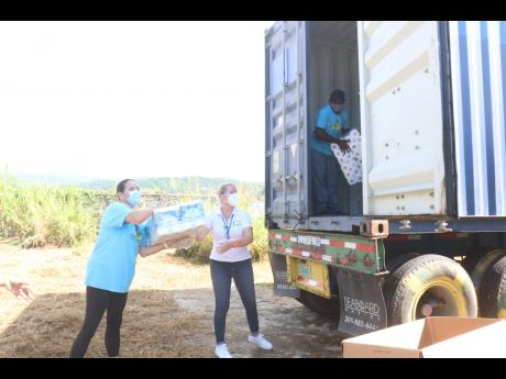 Cornerstone Jamaica’s April Phinney (left) and Hanover Charities’ Katrin Casserly help to unload items from a container.