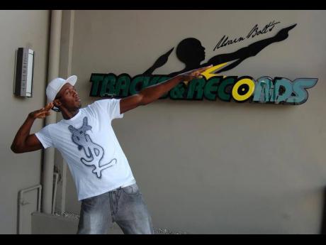 
Usain Bolt poses in front of the Usain Bolt Tracks & Records sign in this 2013 file photo.