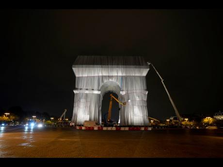 Workers wrap the Arc de Triomphe monument.