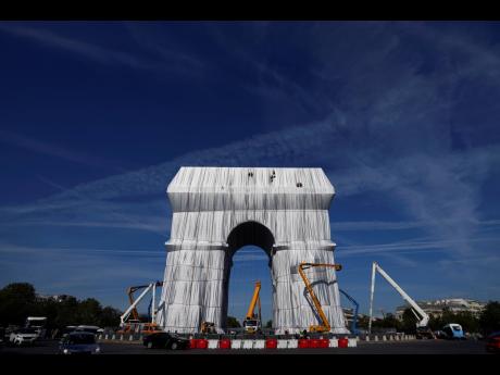 Workers put the final touch to wrap the Arc de Triomphe monument, in Paris last Thursday.