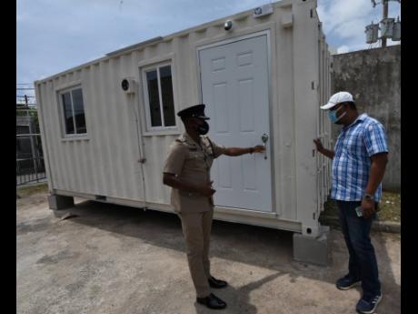 Superintendent Christopher Phillips (left), who is in charge of the 100 Man Police Station in Greater Portmore, St Catherine, and Charroc Construction contractor Raymond Green examine a container that was delivered to the station to be used as an office fo
