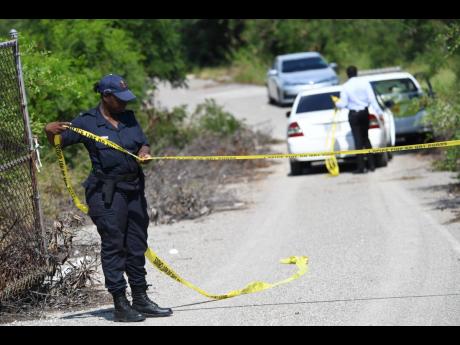A policewoman cordons off the entrance to the now-defunct fishing village off the Portmore toll road in St Catherine, where the body of a woman was discovered in November 2019.