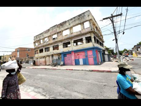 Two women walk past a decaying building on Tower Street in downtown Kingston.