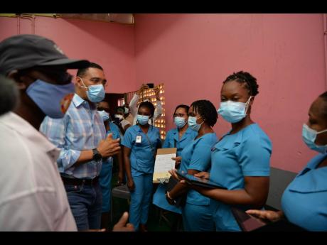 Prime Minister Andrew Holness (second left), gives words of gratitude and encouragement to healthcare workers at the vaccine site at Cross Keys High School during his tour of blitz sites in Manchester on September 16. 
