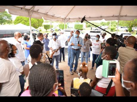 Prime Minister Andrew Holness (centre), addresses residents gathered at the Cross Keys High School to receive their COVID-19 vaccine during his tour of blitz sites in Manchester on September 16. He was accompanied by Local Government and Rural Development 