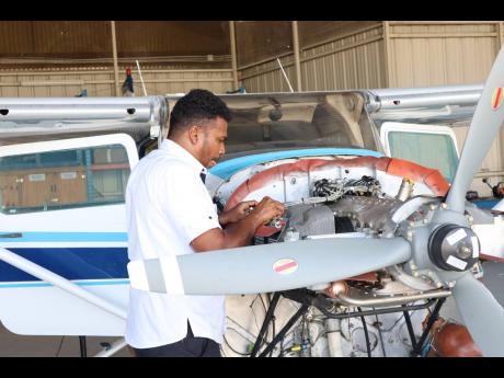 Maintenance Director at the Aeronautical School of the West Indies Christopher Gooding, works on the Aeronautical School of the West Indies (ASWI) training aircraft at the Tinson Pen Aerodrome. Gooding turned his love for flying into a business opportunity