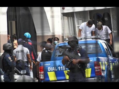 Some of the alleged 33 members of the One Don-Clansman Gang alight from a truck before entering the Home Circuit Court in downtown Kingston on Monday. 